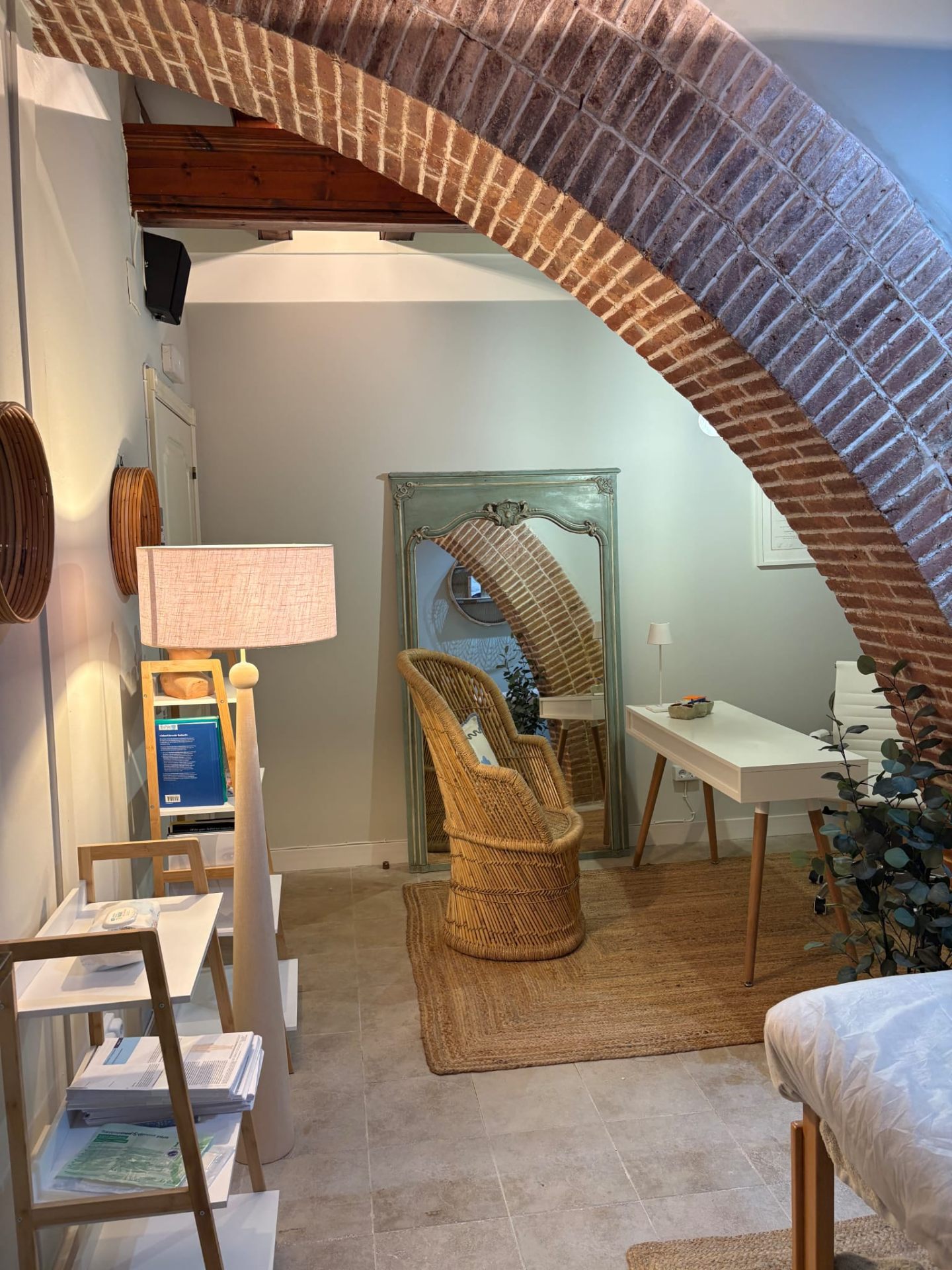 Sala de consulta con arco de ladrillo y espejo veneciano